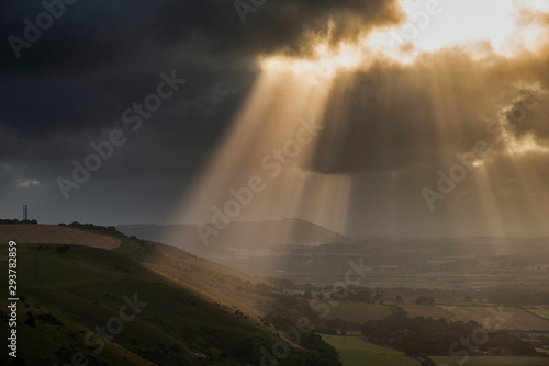 Stunning Summer landscape image of escarpment with dramatic storm clouds and sun beams streaming down