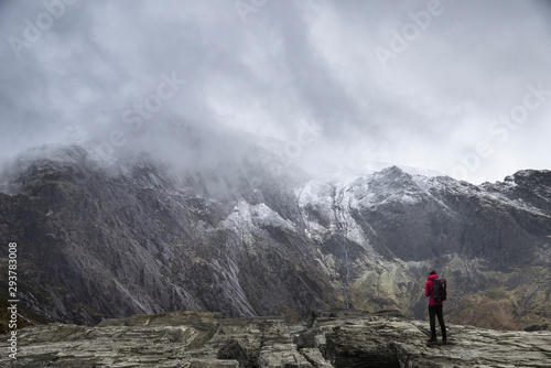Stunning dramatic landscape image of snowcapped Glyders mountain range in Snowdonia during Winter with menacing low clouds hanging at the peaks