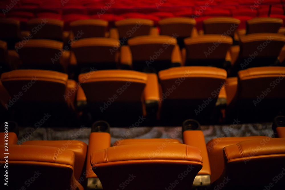Fototapeta premium brown special leather seat in movie theater. pattern of many armchairs in dark room .