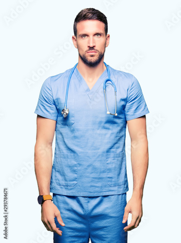Handsome doctor man wearing medical uniform over isolated background Relaxed with serious expression on face. Simple and natural looking at the camera.