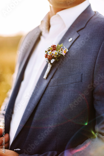 Portrait of the groom in a beautiful suit with a boutonniere close - up. Happy bridegroom