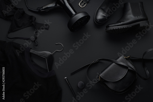 Black monochromatic flatlay on black background. Clothes, accessories and beauty equipment. Black friday sale concept