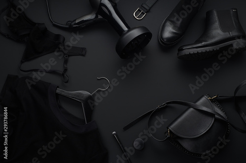 Black monochromatic flatlay on black background. Clothes, accessories and beauty equipment. Black friday sale concept