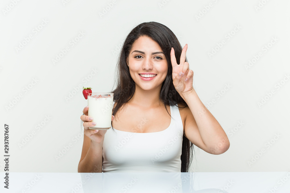 Young hispanic woman holding a smoothie young hispanic woman holding an avocado toast showing victory sign and smiling broadly.< mixto > Young hispanic woman holding a smoothie young hispanic woman holding an avocado toast showing victory sign and smiling broadly.< mixto >