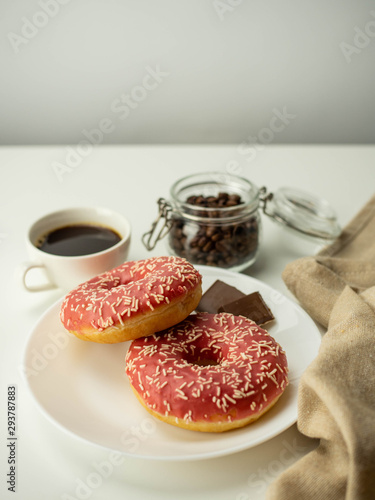 Różowy donut z posypką. Kawa i czekolada. Widok z góry, jasne tło.