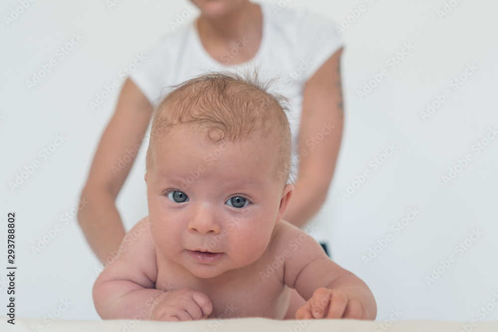 A funny baby is looking straight into the camera and a woman is holding a baby in the background. A funny baby is looking straight into the camera and a woman is holding a baby in the background.