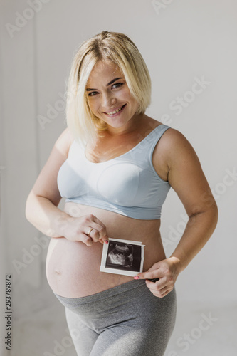 Medium shot pregnant woman holding an ultrasound
