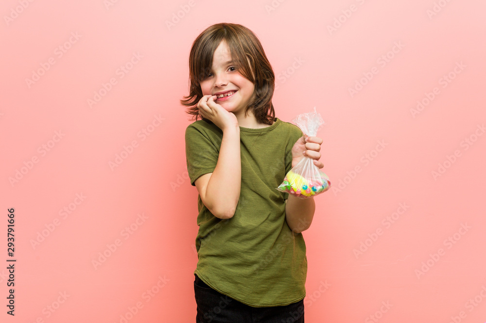 Little boy caucasian holding candies biting fingernails, nervous and very anxious.