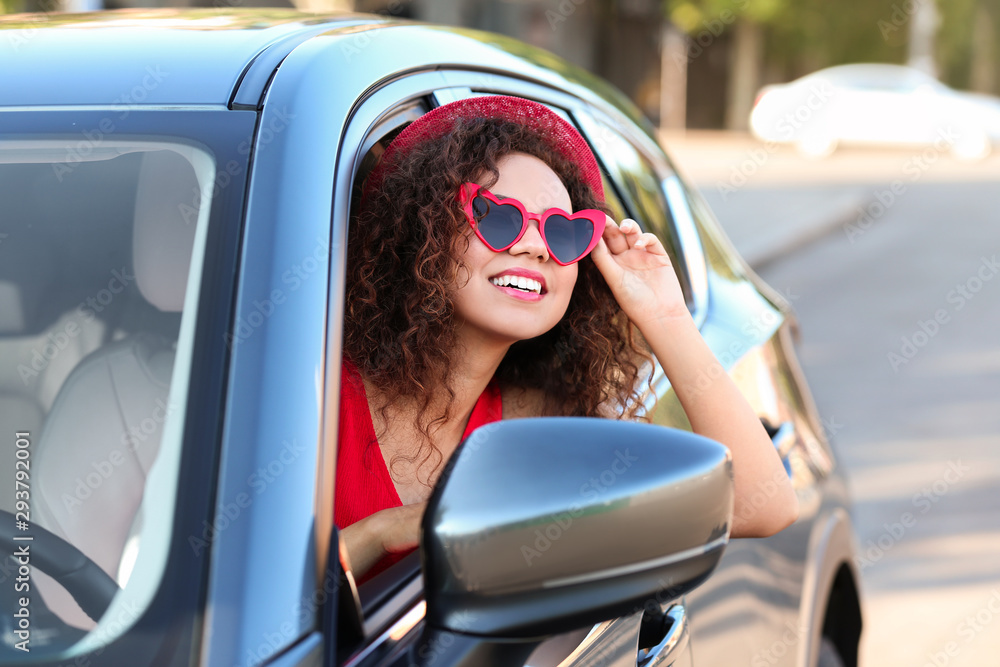 Naklejka premium Young beautiful African-American woman wearing heart shaped glasses in car