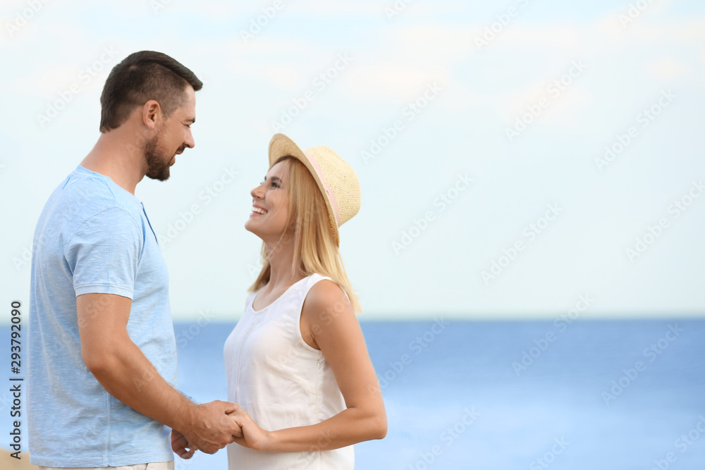 Happy romantic couple spending time together on beach, space for text