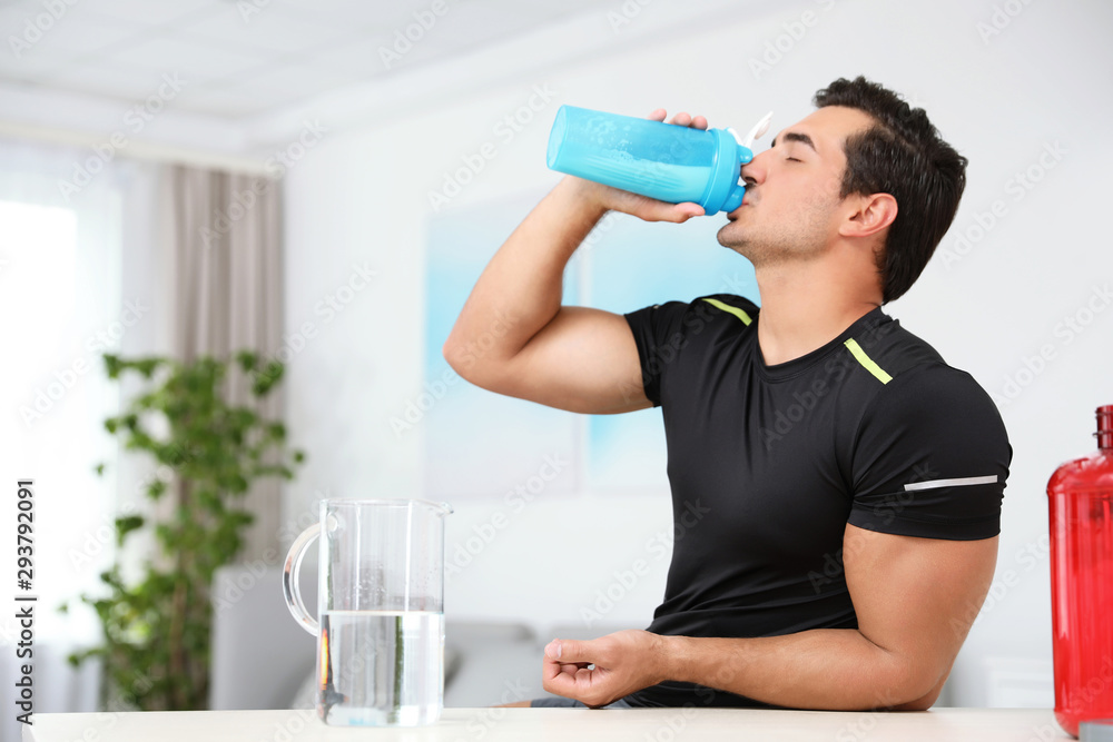 Young athletic man drinking protein shake at home, space for text Young athletic man drinking protein shake at home, space for text