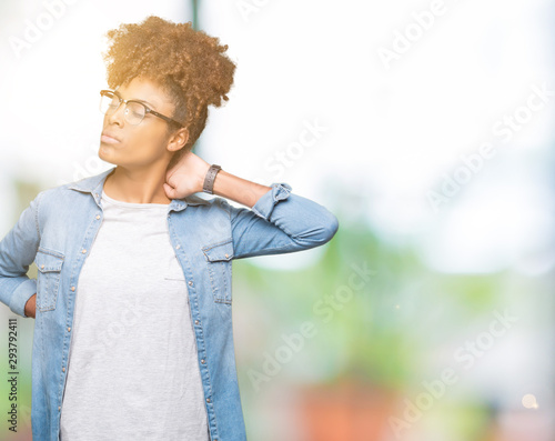 Beautiful young african american woman wearing glasses over isolated background Suffering of neck ache injury, touching neck with hand, muscular pain © Krakenimages.com