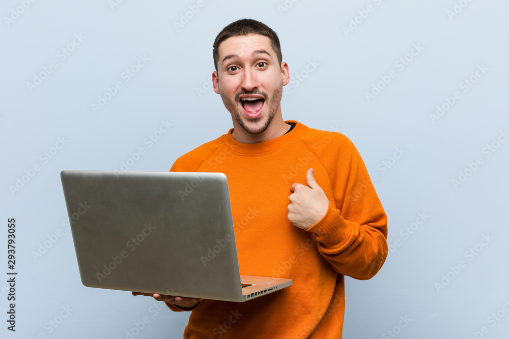 Young caucasian man holding a laptop surprised pointing at himself, smiling broadly. Young caucasian man holding a laptop surprised pointing at himself, smiling broadly.