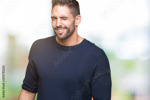 Young handsome man wearing sweater over isolated background winking looking at the camera with sexy expression, cheerful and happy face.