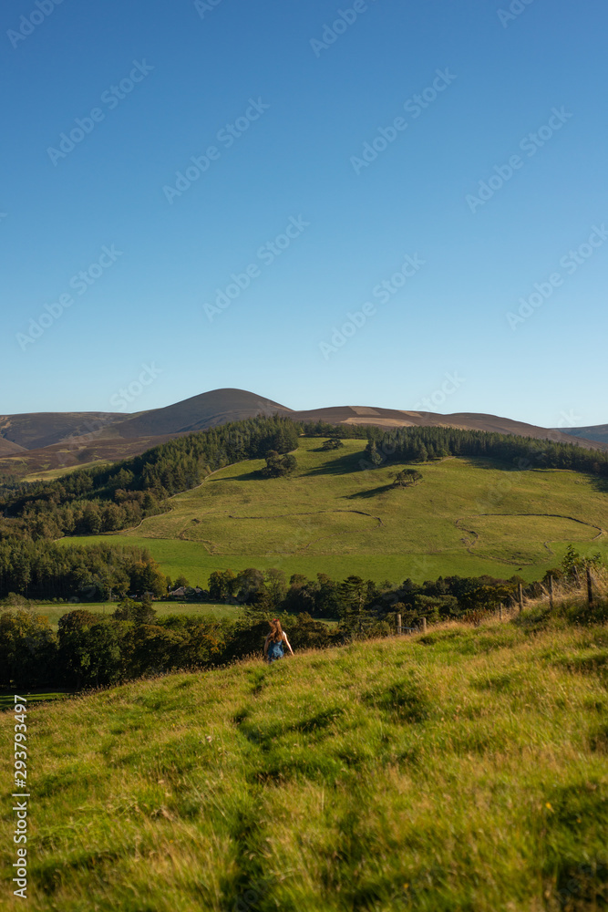Young Woman Walking Through Fields  Over the Crest of a Hill in Beautiful Natural Scenery in Scotland