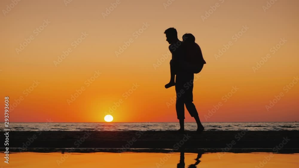 A young man plays with a child, carries him on his shoulders on the beach A young man plays with a child, carries him on his shoulders on the beach