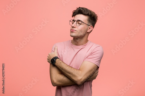 Young cool caucasian man hugs himself, smiling carefree and happy.