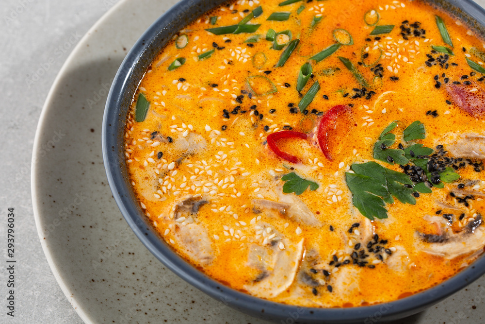Tom Yam kung Spicy Thai soup with shrimp, seafood, coconut milk and chili pepper in bowl. In gray stone background. Horizontal photo.