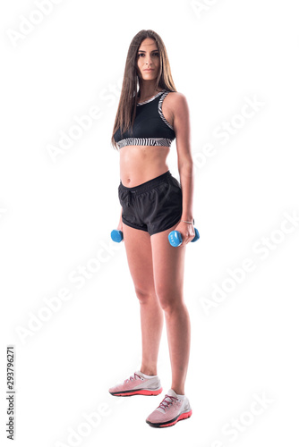 Side view of sporty gym young woman with dumbbells looking at camera. Full body isolated on white background. 