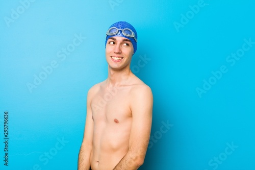 Young swimmer man looks aside smiling, cheerful and pleasant.