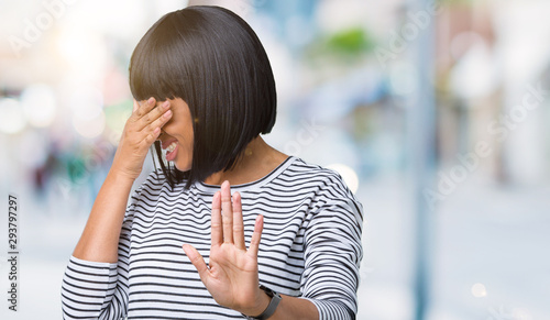 Beautiful young african american woman wearing stripes sweater over isolated background covering eyes with hands and doing stop gesture with sad and fear expression. Embarrassed and negative concept.