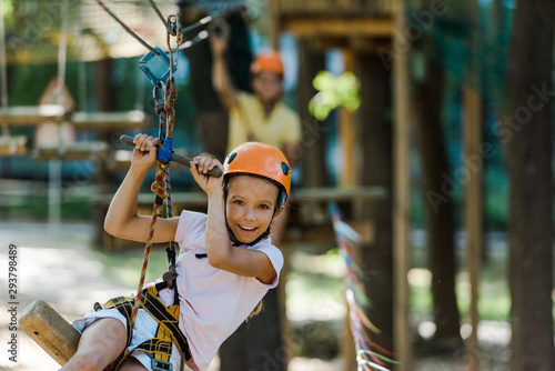 selective focus of happy and cute kid in helmet in adventure park