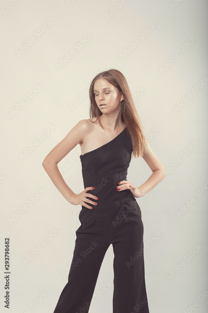 Fototapeta premium Fashionable girl in light tones in studio. Woman with unflappable face. Lifestyle concept in fashion world. Female in suit