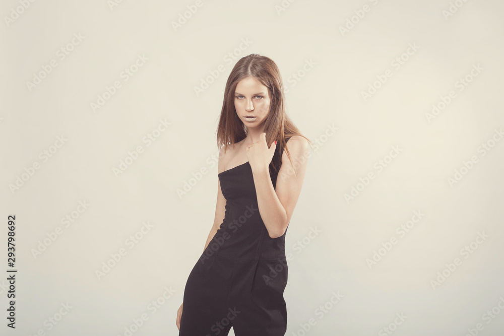 Fototapeta premium Fashionable girl in light tones in studio. Woman with unflappable face. Lifestyle concept in fashion world. Female in suit