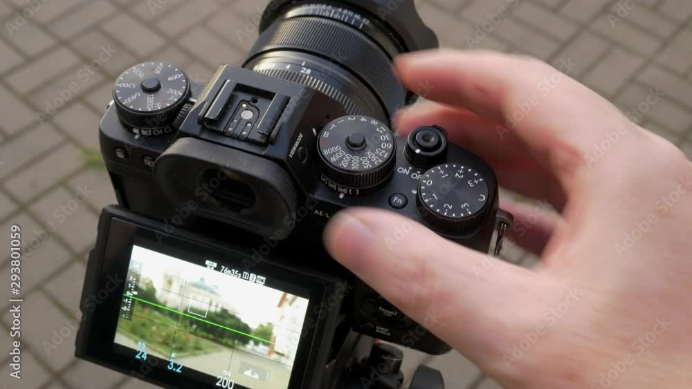 Photographer setting shutter speed to bulb via dial on his camera Photographer setting shutter speed to bulb via dial on his camera