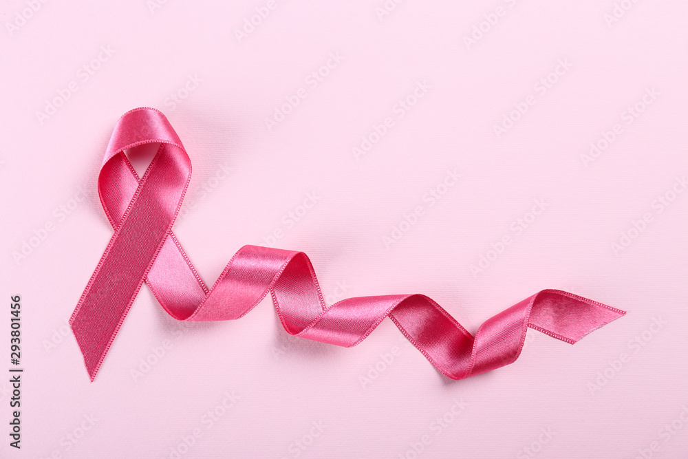 The pink colored ribbon - international symbol of breast cancer awareness and moral support for women. Paper textured background, copy space, close up, top view fat lay. The pink colored ribbon - international symbol of breast cancer awareness and moral support for women. Paper textured background, copy space, close up, top view fat lay.