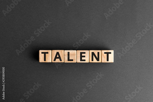 Talent - word from wooden blocks with letters, to be good at something aptitude or skill talent concept, random letters around, white  background