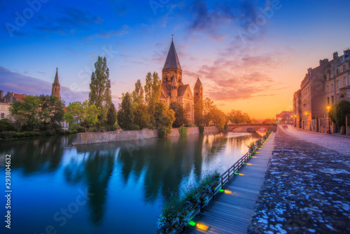 A colourful city view of an ancient Neuf Church on the bank of the Moselle river in Metz in France during the sunrise. Tourist attractions and city life concept