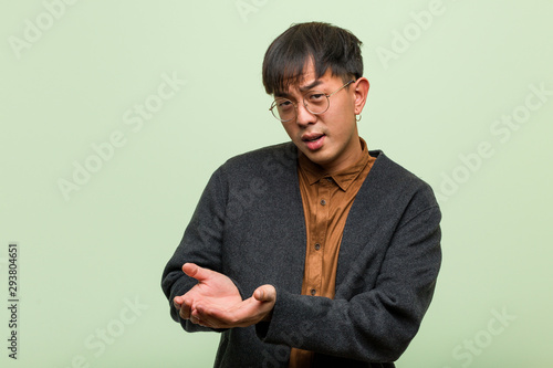Young chinese man against a green wall