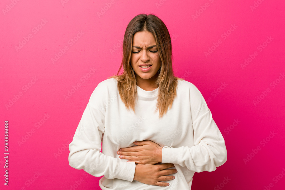Young authentic charismatic real people woman against a wall sick, suffering from stomachache, painful disease concept. Young authentic charismatic real people woman against a wall sick, suffering from stomachache, painful disease concept.