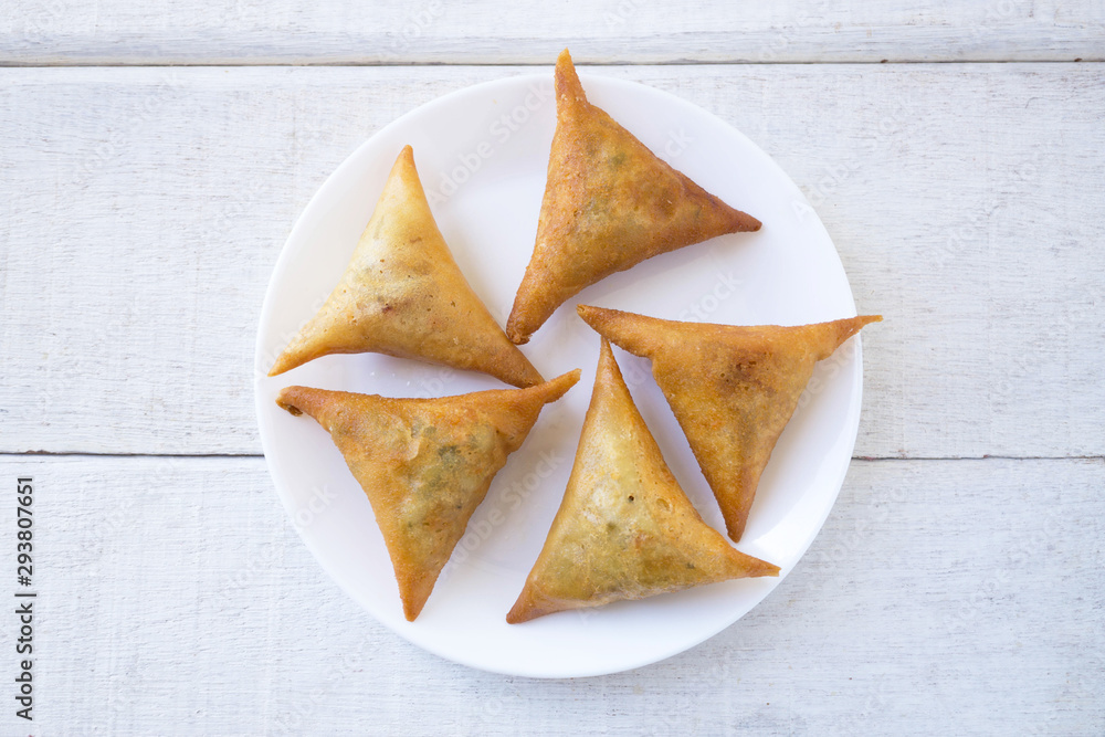 Samosas on white plate on white wood.Top view. Samosas on white plate on white wood.Top view.