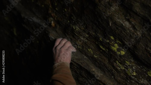 climber grabbing along cracks on rock at night