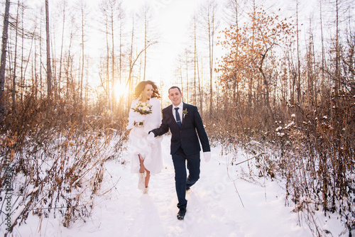 Beautiful wedding couple. Winter wedding of the groom in a beautiful suit and the bride in a beautiful wedding dress. Winter photo shoot newlyweds.