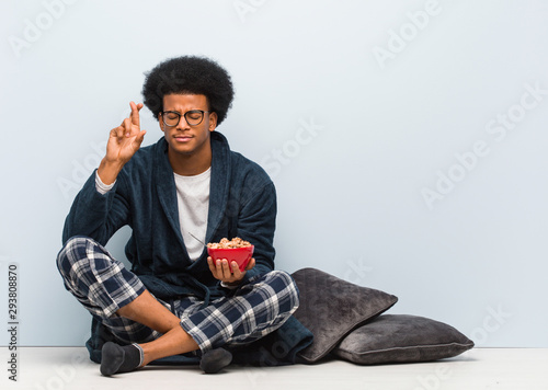 Young black man sitting and having a breakfast crossing fingers for having luck © Asier