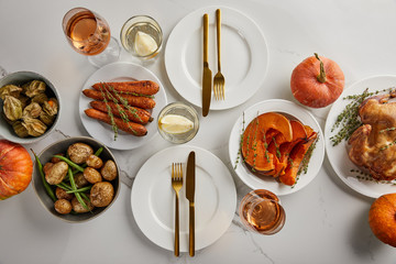 top view of festive thanksgiving dinner with baked vegetables and grilled turkey served on white marble table