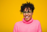 Young african american woman wearing a pink sweater funny and friendly sticking out tongue.