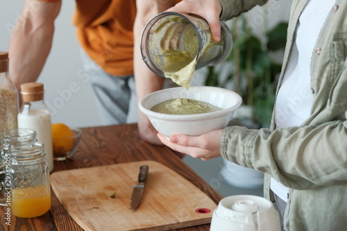 A girl pours smoothie from a blender into a plate
