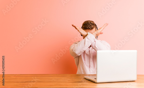 Young man working in a call center keeping two arms crossed, denial concept. photo