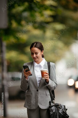 Young businesswoman drinking coffee and using phone