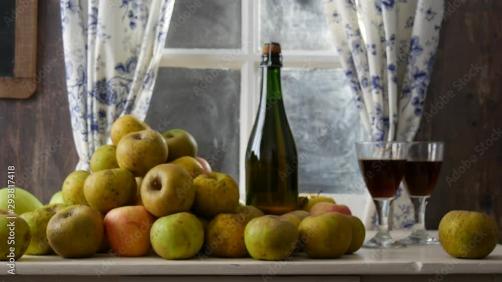 Moving camera slider showing bottle and glasses of cider with apples. In rustic house Moving camera slider showing bottle and glasses of cider with apples. In rustic house