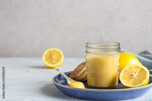 Canvastavla A jar of lemon curd or custard with a spoon and cookies on a blue plate and fresh lemon