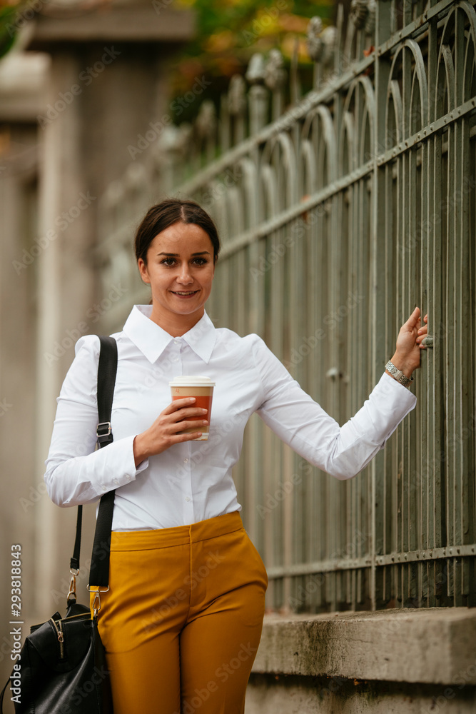 Portrait of young woman walking on the street with coffee