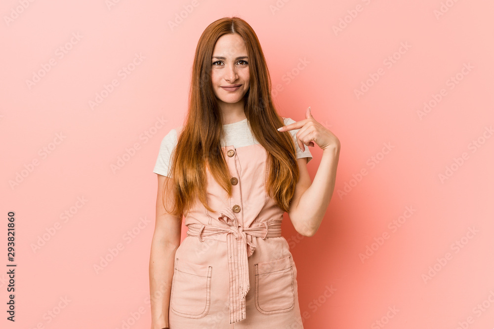 Young ginger woman with freckles person pointing by hand to a shirt copy space, proud and confident Young ginger woman with freckles person pointing by hand to a shirt copy space, proud and confident