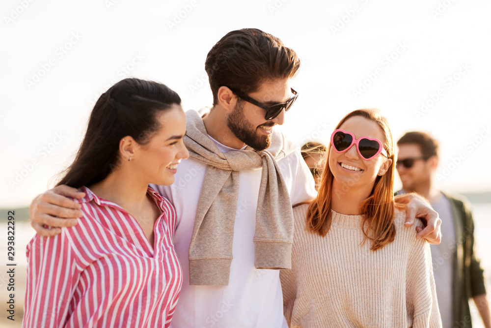 friendship, leisure and people concept - group of happy friends walking along beach in summer friendship, leisure and people concept - group of happy friends walking along beach in summer