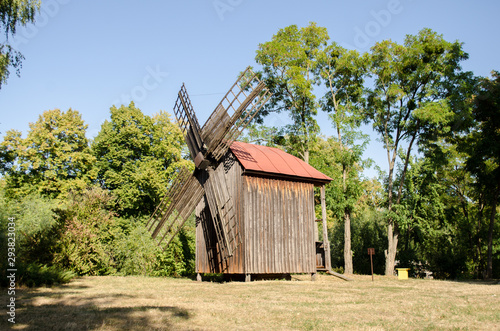 Old ruined abandoned wooden mill among the trees in park photo