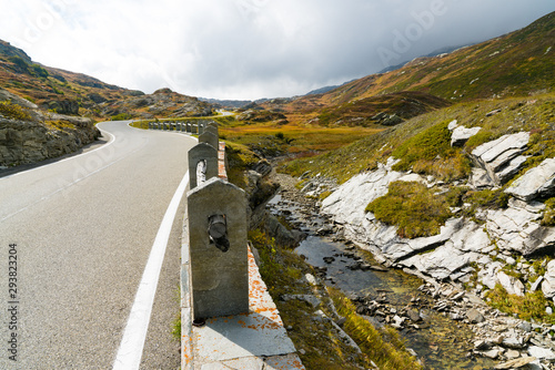 two-lane road leading over a high remote and wild mountain pass in the Swiss Alps in autumn photo